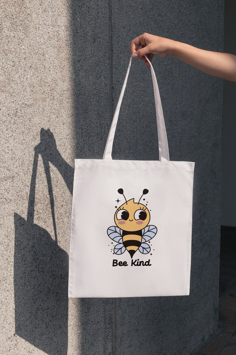 May include: White tote bag with a cartoon bee design and the text "Bee Kind".