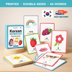 May include: A set of Korean first words flashcards with colorful illustrations. The cards feature images of a rainbow, grapes, a strawberry, a flower, a sun, a cow, and a pair of lips. The box reads "Korean FIRST WORDS flashcards".