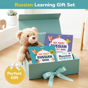 Op de afbeelding: Een tealblauwe geschenkdoos met een lichtbruine teddybeer met een bruine strik en drie Russische taalleerboeken. De boeken heten "My First Russian Book", "My First Russian Alphabet Book" en "Russian First Words flashcards". De doos heeft een tealblauwe strik.