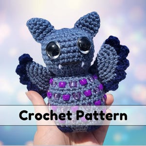 May include: Crochet pattern for a blue and purple bat amigurumi toy with googly eyes. The bat has a beaded body and is holding its wings out.