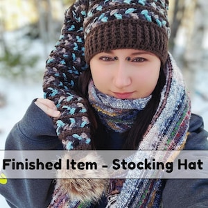 May include: A handmade stocking hat with a long, pointed top. The hat is brown with blue and white accents. The text "Finished Item - Stocking Hat" is displayed at the bottom of the image. A matching scarf is also visible.