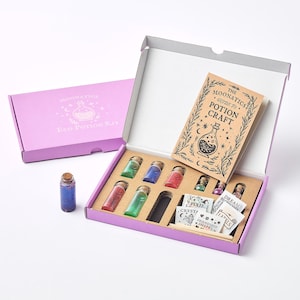 May include: A purple box set containing potion-making supplies. Inside, there are several small glass bottles filled with colorful liquids and glitter, a small book titled "The Moonatics Guide to Potion Craft", and other crafting materials.