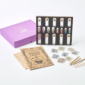 Può includere: Una scatola viola con l'etichetta "Moonatics Eco Potion Kit" accanto a un espositore nero contenente piccole bottiglie di vetro con tappi di sughero. È presente anche un libretto intitolato "The Moonatics Guide to Potion Craft" e piccole etichette.