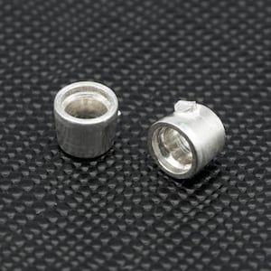 Puede incluir: Dos anillos de metal plateado con un acabado liso y redondeado. Los anillos son ligeramente diferentes en tamaño y tienen un pequeño borde alrededor del borde superior.