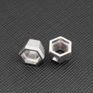 Könnte beinhalten: Zwei silberne sechseckige Ringe mit einem hohlen Zentrum. Die Ringe liegen auf einer schwarzen, strukturierten Oberfläche.