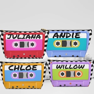 May include: Four cosmetic bags with cassette tape designs. Each bag features a different color: red, blue, yellow, and green. The names "JULIANA", "ANDIE", "CHLOE", and "WILLOW" are printed on each bag. The bags have a black and white checkered pattern.