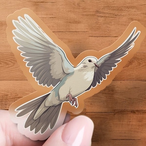 May include: A white dove with gray wings in flight, depicted in a sticker format.