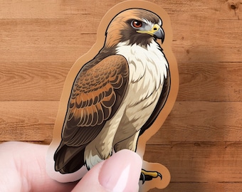 May include: A sticker of a brown and white hawk with a yellow beak and red eyes. The hawk is perched on a branch with its wings spread out.