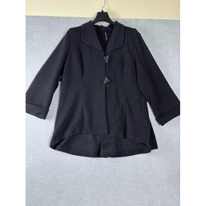以下が含まれることがあります： ノッチカラーと3/4スリーブの黒いジャケット。 ジャケットはテクスチャード加工された生地で、3つの三角形のボタンで留められています。 ヘムラインは後ろが少し長くなっています。