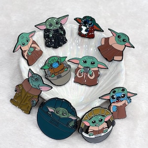 Op de afbeelding: Een verzameling emaille pins met het personage Grogu, ook bekend als Baby Yoda, uit de Star Wars-serie. De pins tonen Grogu in verschillende poses en outfits, met levendige kleuren en gedetailleerde ontwerpen. De pins zijn gerangschikt op een wit, getextureerd oppervlak.