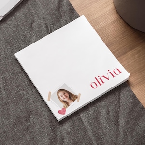 Op de afbeelding: Wit notitieblok met een rood hart en een foto van een meisje met de naam "olivia" in rood gedrukt.
