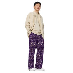 May include: A person wearing a beige button-down shirt and purple pants with a white and yellow pattern. The pants have a wide leg style.