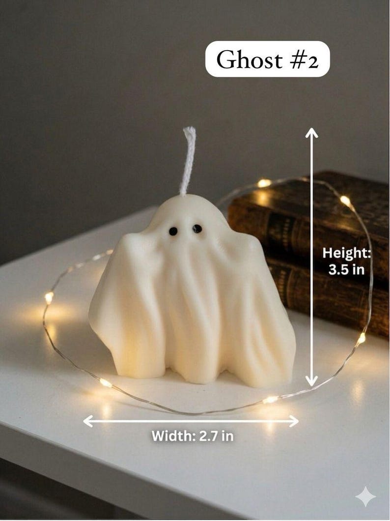 K&ouml;nnte beinhalten: Eine cremefarbene, geisterf&ouml;rmige Kerze mit zwei schwarzen Augen und einem wei&szlig;en Docht. Die Kerze ist mit Ghost #2 beschriftet und zeigt Messpfeile f&uuml;r eine H&ouml;he von 3,5 Zoll und eine Breite von 2,7 Zoll, umgeben von einer d&uuml;nnen Lichterkette.