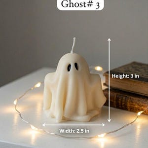 K&ouml;nnte beinhalten: Eine cremewei&szlig;e, geisterf&ouml;rmige Kerze mit zwei schwarzen, ovalen Augen und einem einzelnen wei&szlig;en Docht an der Oberseite. Die Kerze ist mit Ghost# 3 beschriftet und zeigt Messpfeile f&uuml;r eine H&ouml;he von 7,62 cm und eine Breite von 6,35 cm.