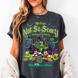 May include: Dark grey t-shirt with a Halloween-themed design. The shirt displays the text "Mickey's Not-So-Scary Halloween Party" in green and purple. The graphic includes cartoon characters, a castle, bats, and pumpkins. The Walt Disney World logo is at the bottom.