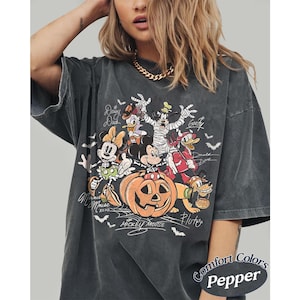 May include: A charcoal gray t-shirt featuring a Halloween-themed graphic of Disney characters including Mickey Mouse, Minnie Mouse, Donald Duck, Daisy Duck, Goofy, and Pluto. The characters are dressed in costumes around a large orange pumpkin.