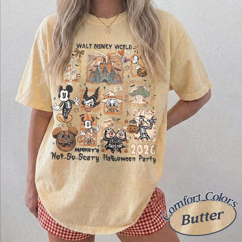 Pu&ograve; includere: T-shirt giallo chiaro con una grafica Disney a tema Halloween. Il design include vari personaggi in costume e il testo "WALT DISNEY WORLD", "MICKEY'S Not-So-Scary Halloween Party 2026" e "Comfort Colors Butter".