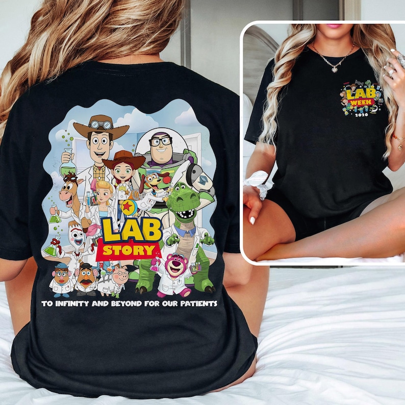 May include: Black t-shirt featuring a colorful graphic of Toy Story characters in lab coats with the words "LAB STORY" and "TO INFINITY AND BEYOND FOR OUR PATIENTS". A smaller graphic on the chest reads "LAB WEEK 2020".
