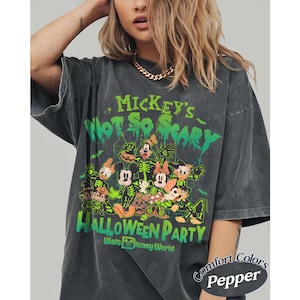 K&ouml;nnte beinhalten: Dunkelgraues T-Shirt mit einem Halloween-Design mit Micky Maus und Freunden. Auf dem Shirt steht "Mickey's Not So Scary Halloween Party" in Gr&uuml;n und Orange. Das Shirt ist mit "Comfort Colors Pepper" gekennzeichnet.