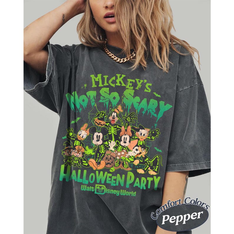 K&ouml;nnte beinhalten: Dunkelgraues T-Shirt mit einem Halloween-Design mit Micky Maus und Freunden. Auf dem Shirt steht "Mickey's Not So Scary Halloween Party" in Gr&uuml;n und Orange. Das Shirt ist mit "Comfort Colors Pepper" gekennzeichnet.