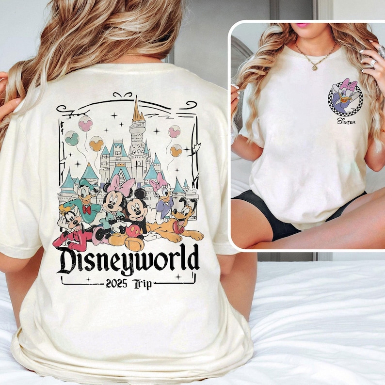 May include: White t-shirt with a graphic of Mickey Mouse and friends in front of Cinderella's Castle. The text "Disneyworld 2025 Trip" is printed below the graphic. The back of the shirt has a graphic of a cartoon character with the text "Sister".