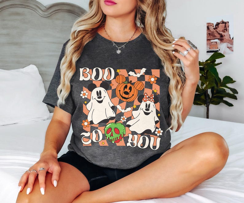 May include: Dark gray t-shirt with a Halloween-themed graphic. The design features the text "BOO TO YOU" with cartoon ghosts, Mickey Mouse pumpkins, and a green skull. The background has an orange and white checkered pattern.