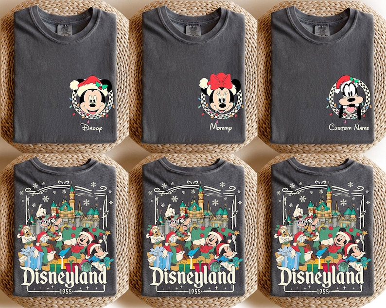 May include: Six dark gray t-shirts with Disney character designs. Three shirts feature Mickey, Minnie, and Goofy with Christmas lights and text. The other three shirts display a Disneyland design with characters and the text "Disneyland 1955".
