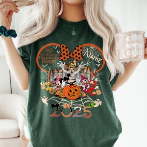 May include: Dark green t-shirt with a Halloween-themed design featuring Disney characters like Mickey and Minnie Mouse. The design includes a pumpkin, castle, and the text "Not So Scary Halloween Party!" and "2025".