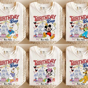 K&ouml;nnte beinhalten: Sechs wei&szlig;e T-Shirts mit farbenfrohen Disney-Charakter-Designs. Jedes Shirt zeigt den Text "BIRTHDAY Boy" oder "BIRTHDAY Girl" in Rot und Blau, mit Platz f&uuml;r einen Namen. Die Designs umfassen Micky Maus, Donald Duck und Pluto.