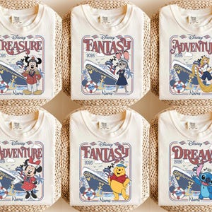 May include: Six off-white t-shirts with Disney cruise-themed designs. Each shirt features a different character and the words "TREASURE", "FANTASY", "ADVENTURE", and "DREAM" with the year "2026". The designs include Mickey Mouse, Judy Hopps, Rapunzel, Minnie Mouse, Winnie the Pooh, and Stitch.