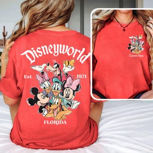 May include: Red t-shirt featuring a Disney World graphic with Mickey Mouse, Minnie Mouse, Donald Duck, Daisy Duck, Goofy, and Pluto. The back of the shirt says "Disneyworld Florida Est. 1971". The front has a smaller graphic and the words "Custom Name".