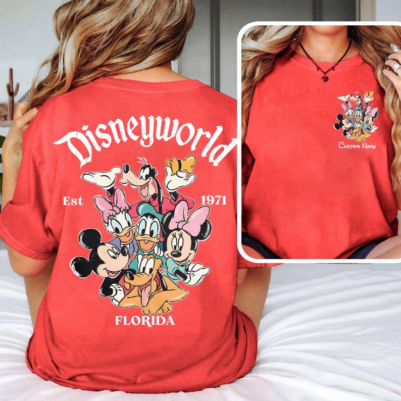 May include: Red t-shirt featuring a Disney World graphic with Mickey Mouse, Minnie Mouse, Donald Duck, Daisy Duck, Goofy, and Pluto. The back of the shirt says "Disneyworld Florida Est. 1971". The front has a smaller graphic and the words "Custom Name".