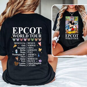 Pode incluir: Camiseta preta com um gr&aacute;fico branco do Mickey Mouse e o texto "EPCOT WORLD TOUR". O gr&aacute;fico inclui &iacute;cones que representam diferentes pa&iacute;ses e cidades ao redor do mundo.