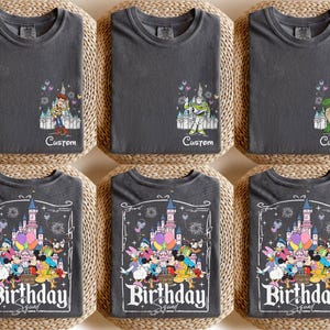 K&ouml;nnte beinhalten: Sechs anthrazitgraue T-Shirts werden gezeigt. Drei Shirts zeigen Disney-Figuren mit dem Wort "Custom" darunter. Die anderen drei Shirts haben ein "Birthday Squad"-Design mit Disney-Figuren und einem Schloss.