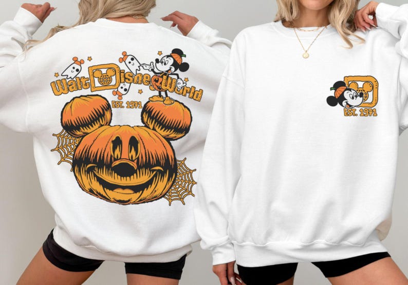 May include: White sweatshirt featuring a large orange pumpkin with Mickey Mouse ears and a smiling face. The back of the sweatshirt says "Walt Disney World" with Mickey Mouse and ghosts. The front has a small Mickey Mouse graphic.