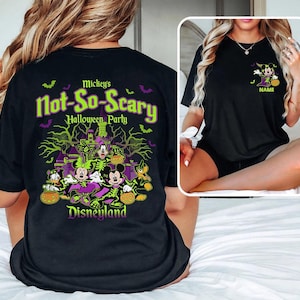 May include: Black t-shirt featuring a Halloween design with Mickey Mouse, Minnie Mouse, Donald Duck, and Goofy. The shirt has the text "Mickey's Not-So-Scary Halloween Party" and "Disneyland" in green and purple. A smaller image of Minnie Mouse is on the front.