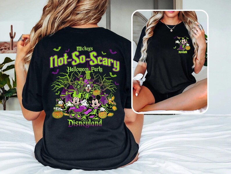 May include: Black t-shirt featuring a Halloween design with Mickey Mouse, Minnie Mouse, Donald Duck, and Goofy. The shirt has the text "Mickey's Not-So-Scary Halloween Party" and "Disneyland" in green and purple. A smaller image of Minnie Mouse is on the front.