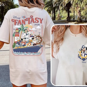 May include: Cream-colored t-shirt featuring a Disney Fantasy design. The back graphic showcases Disney characters on a ship with a lighthouse and the text "FANTASY 2026." A smaller graphic on the front includes Mickey Mouse and an anchor.