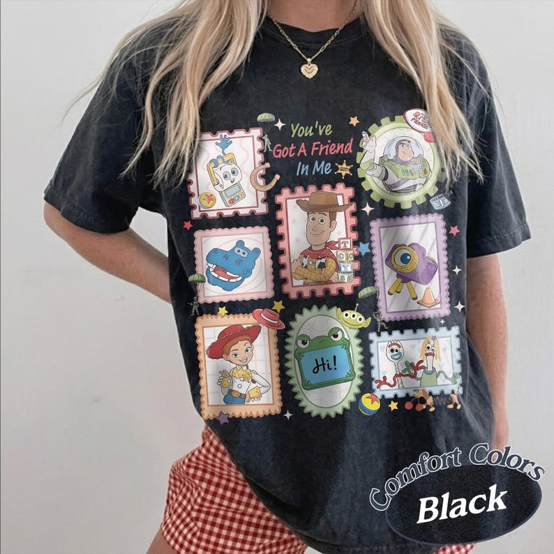 May include: A black short-sleeve t-shirt featuring a graphic print of various characters and objects from Toy Story arranged in postage stamp frames. The text "You've Got A Friend In Me" is printed in the center. The shirt has a vintage wash.