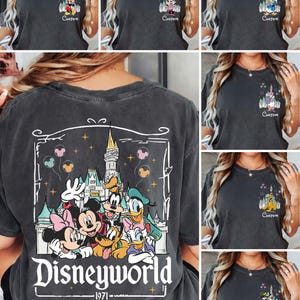 May include: Dark grey t-shirts featuring Disney characters. The front of the shirts display Mickey Mouse, Minnie Mouse, Donald Duck, Daisy Duck, Goofy, and Pluto with a castle and the word "Custom". The back of the shirt has a large graphic of Disney characters and the words "Disneyworld 1971".