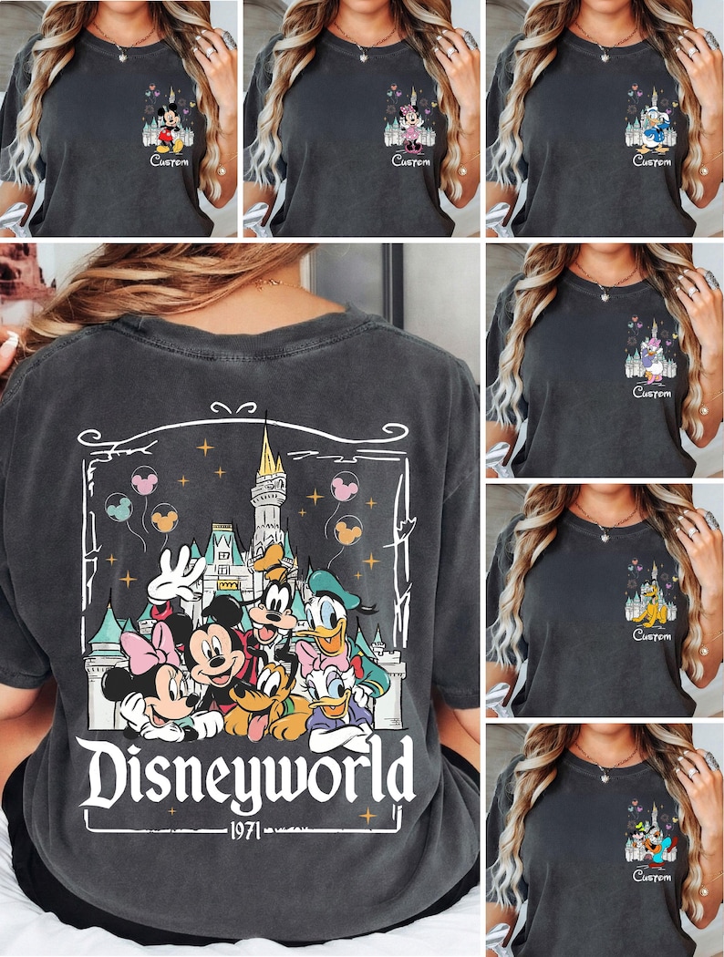 May include: Dark grey t-shirts featuring Disney characters. The front of the shirts display Mickey Mouse, Minnie Mouse, Donald Duck, Daisy Duck, Goofy, and Pluto with a castle and the word "Custom". The back of the shirt has a large graphic of Disney characters and the words "Disneyworld 1971".