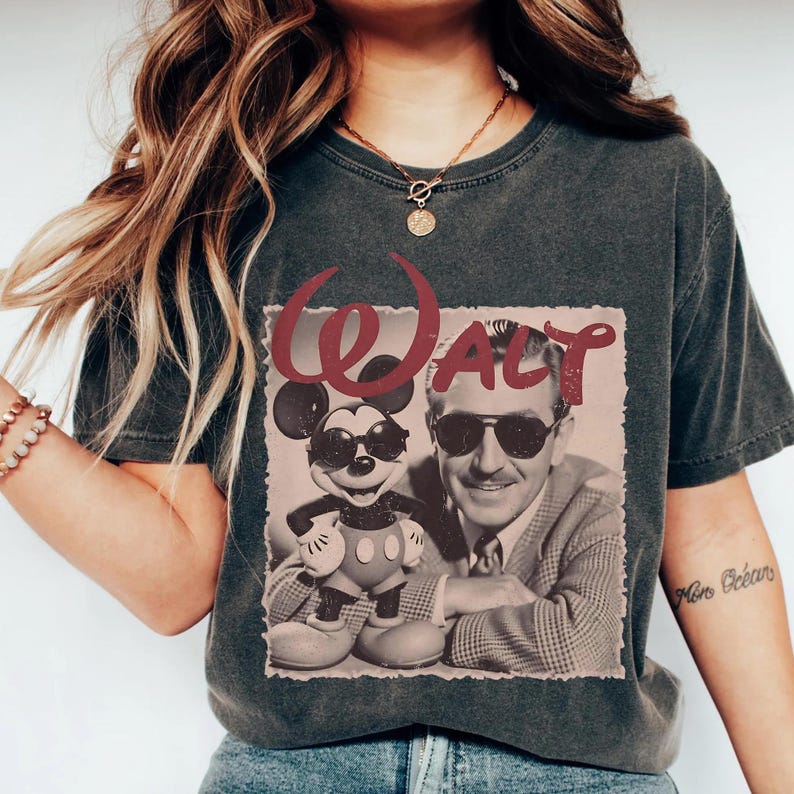 May include: Dark gray t-shirt featuring a vintage-style graphic of Mickey Mouse and Walt Disney wearing sunglasses. The word "Walt" is printed in a burgundy color above the image. The shirt has a classic, relaxed fit.