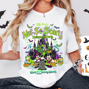 May include: White t-shirt with a vibrant graphic for Mickey's Not-So-Scary Halloween Party at Walt Disney World. The design features Mickey Mouse, Donald Duck, and Goofy in Halloween costumes, with bats and a spooky castle.