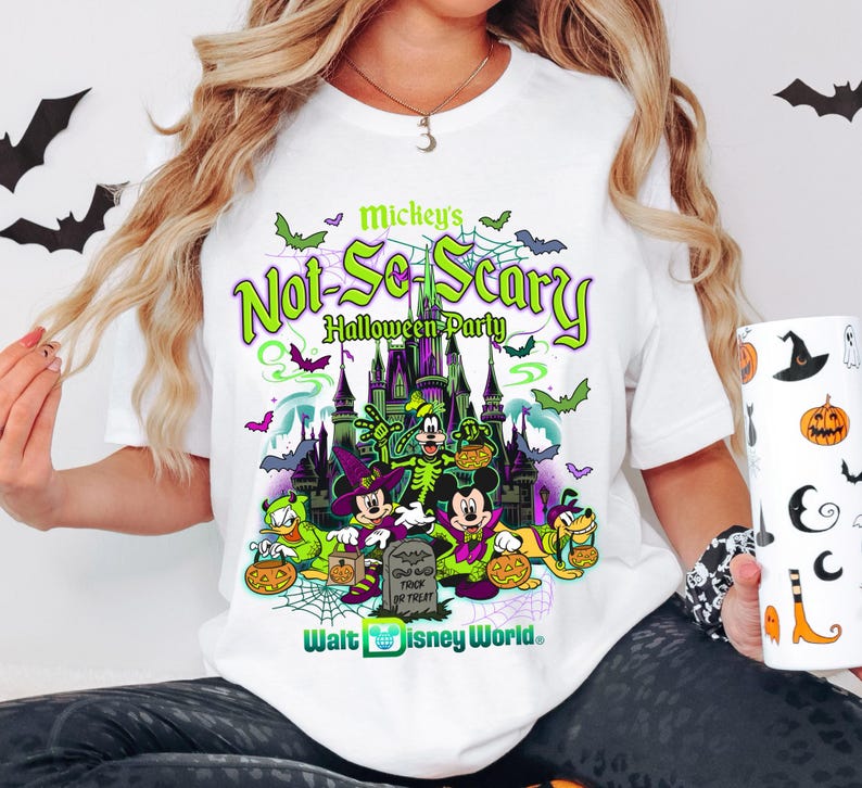 May include: White t-shirt with a vibrant graphic for Mickey's Not-So-Scary Halloween Party at Walt Disney World. The design features Mickey Mouse, Donald Duck, and Goofy in Halloween costumes, with bats and a spooky castle.