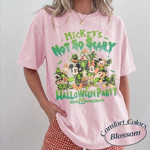 K&ouml;nnte beinhalten: Hellrosa T-Shirt mit einem gr&uuml;nen Aufdruck von Disney-Figuren in Halloween-Kost&uuml;men. Der Text lautet "Mickey's Not So Scary Halloween Party" und "Walt Disney World". Das Shirt ist ein Comfort Colors Blossom.