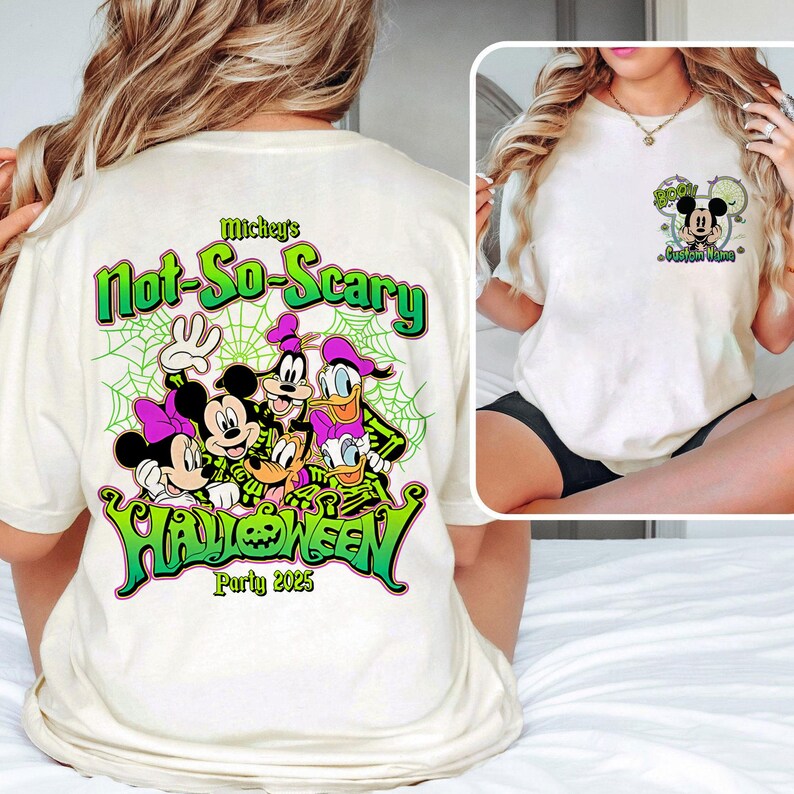 Op de afbeelding: Cr&egrave;mekleurig T-shirt met een Halloween-ontwerp met Mickey Mouse, Minnie Mouse, Goofy, Donald Duck en Daisy Duck. Het shirt heeft de tekst "Mickey's Not-So-Scary Halloween Party 2025" in groen en zwart.