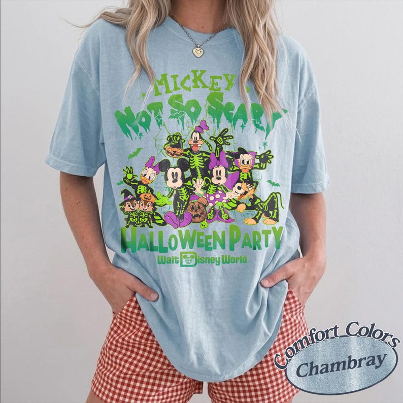 Op de afbeelding: Lichtblauw T-shirt met een Halloween-afbeelding met Mickey Mouse en vrienden in skeletkostuums. De tekst luidt "Mickey's Not So Scary Halloween Party" en "Walt Disney World". Het shirt is een Comfort Colors Chambray.
