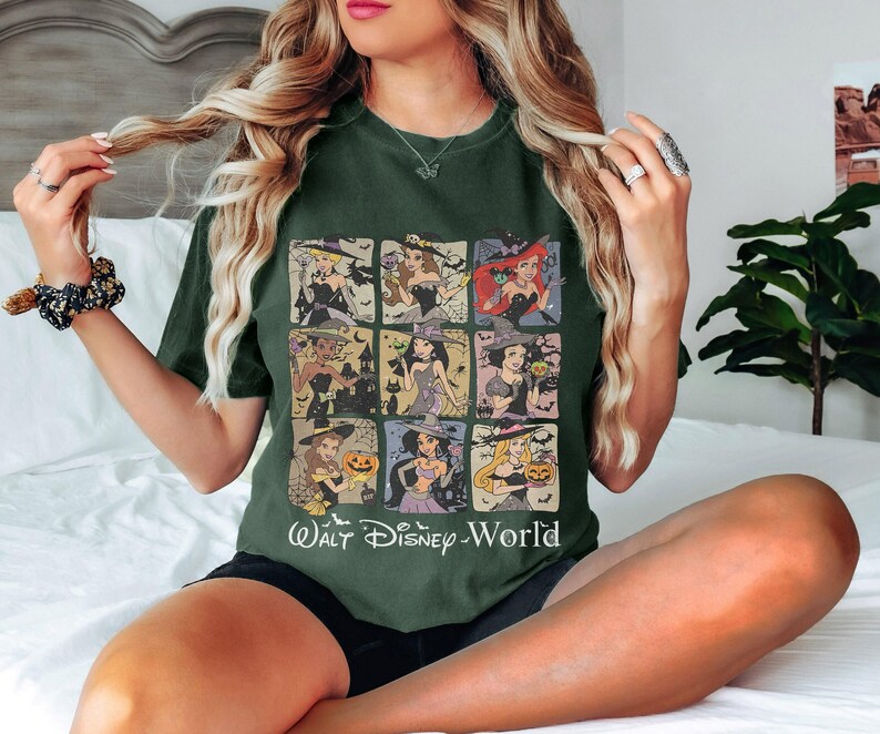 May include: A dark green t-shirt with a graphic print of various Disney princesses dressed as witches. The text "Walt Disney World" is printed below the graphic.