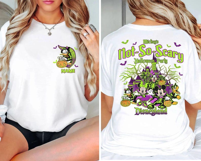May include: White t-shirt featuring a Halloween-themed design. The front displays a cartoon character with a witch hat and a pumpkin. The back features the text "Mickey's Not-So-Scary Halloween Party" with Disney characters and a haunted castle.