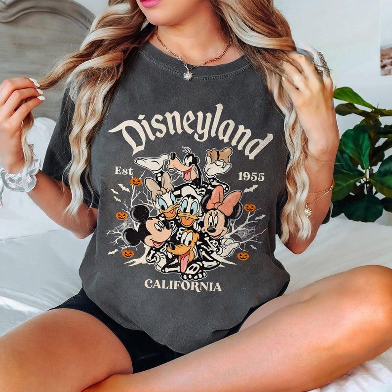 K&ouml;nnte beinhalten: Ein dunkelgraues T-Shirt mit einem Vintage-Disneyland-Motiv mit Mickey Mouse, Minnie Mouse, Donald Duck, Goofy und Pluto. Das Motiv enth&auml;lt den Text "Disneyland", "Est. 1955" und "California".